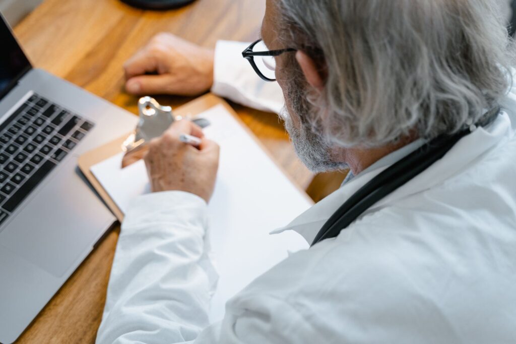 Doctor writing notes on a clipboard at a desk